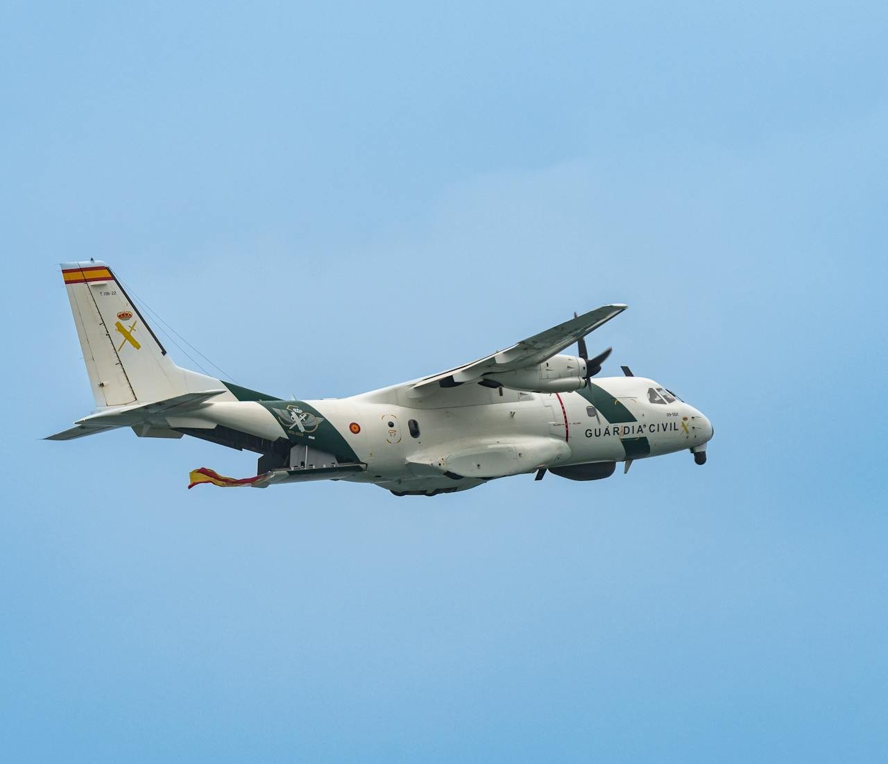 Spanish Guardia Civil aircraft flying against a blue sky, showcasing military aviation in action.